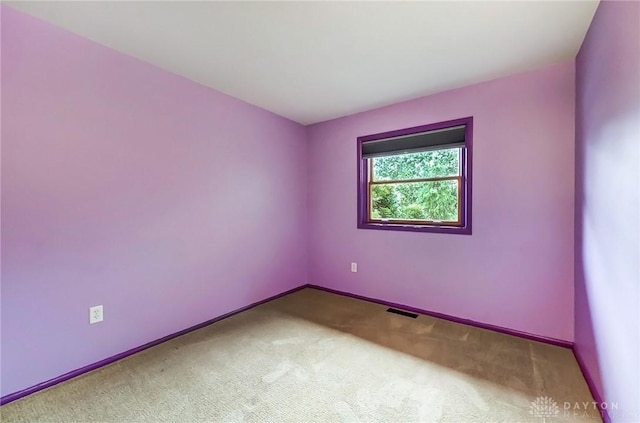 spare room featuring carpet, visible vents, and baseboards