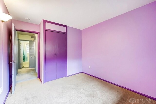 unfurnished bedroom featuring light carpet and a closet