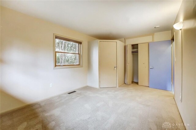 unfurnished bedroom featuring light carpet, a closet, and visible vents