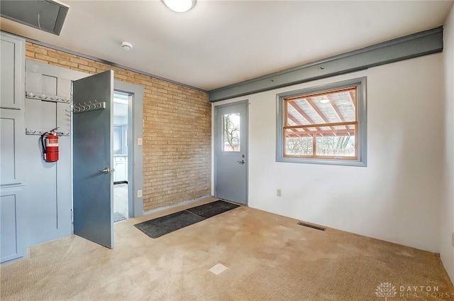 entryway with brick wall, carpet floors, and visible vents