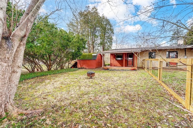 exterior space featuring a storage shed, an outdoor fire pit, an outbuilding, fence, and a front lawn