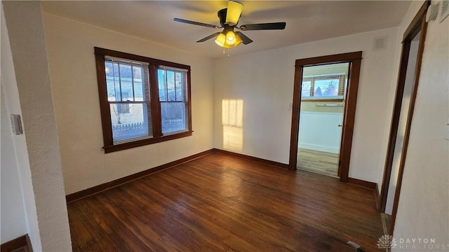 unfurnished room featuring baseboards, visible vents, and dark wood finished floors