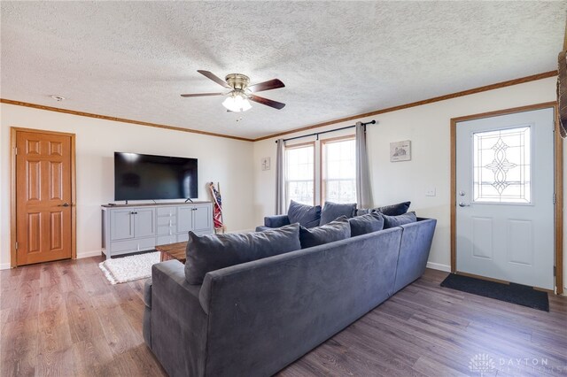 living room with a textured ceiling, ornamental molding, wood finished floors, and a ceiling fan