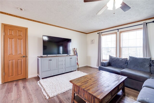 living room with baseboards, ornamental molding, and wood finished floors