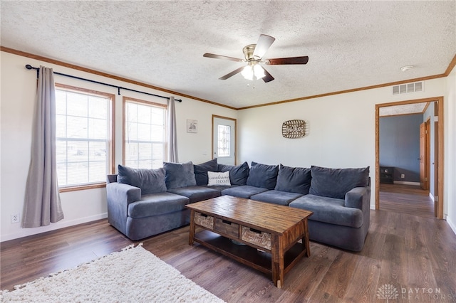 living room with a textured ceiling, ornamental molding, wood finished floors, and visible vents