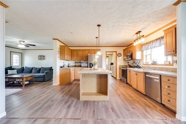 kitchen with a kitchen island, open floor plan, stainless steel appliances, light wood-style floors, and a sink