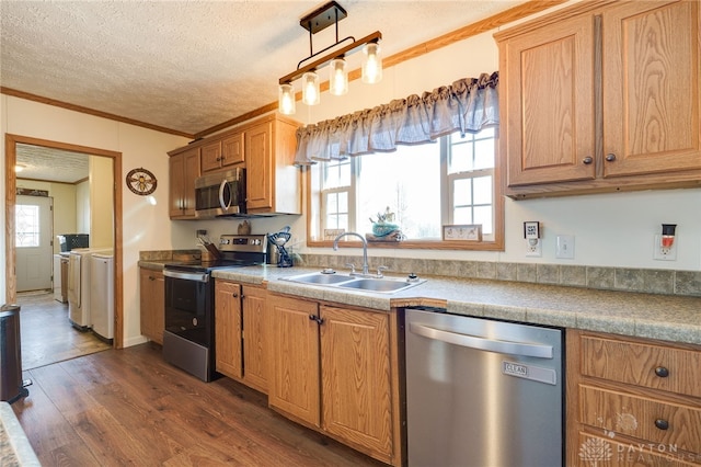 kitchen featuring appliances with stainless steel finishes, ornamental molding, dark wood-style flooring, washer and dryer, and a sink