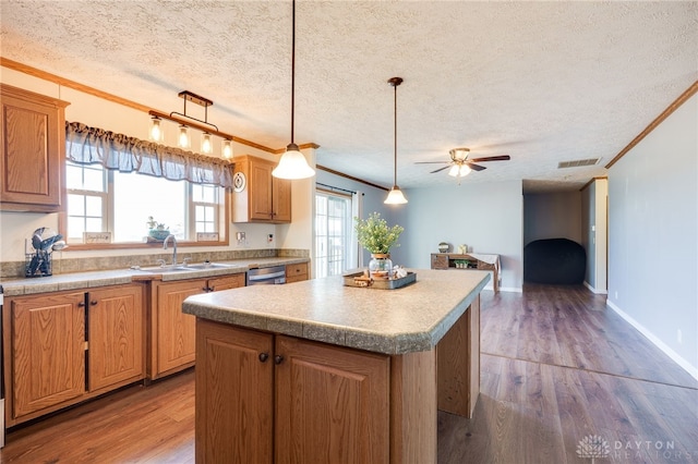 kitchen with a sink, visible vents, dishwasher, and wood finished floors