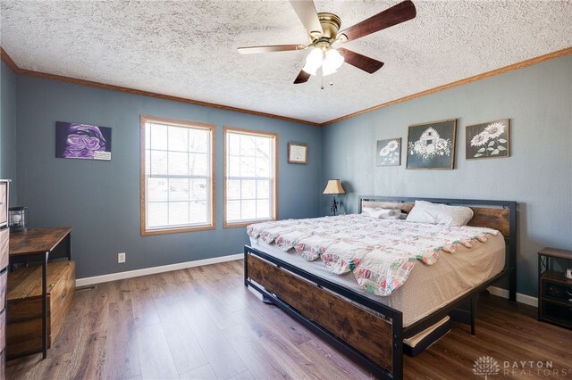 bedroom featuring ornamental molding, a textured ceiling, baseboards, and wood finished floors