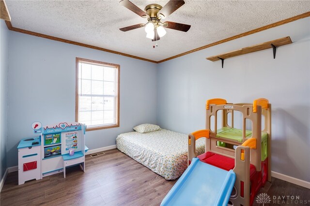 bedroom with a textured ceiling, ornamental molding, wood finished floors, and baseboards