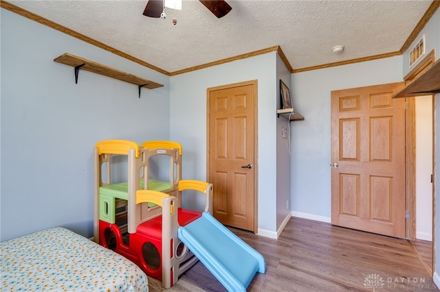 interior space featuring crown molding, a textured ceiling, baseboards, and wood finished floors