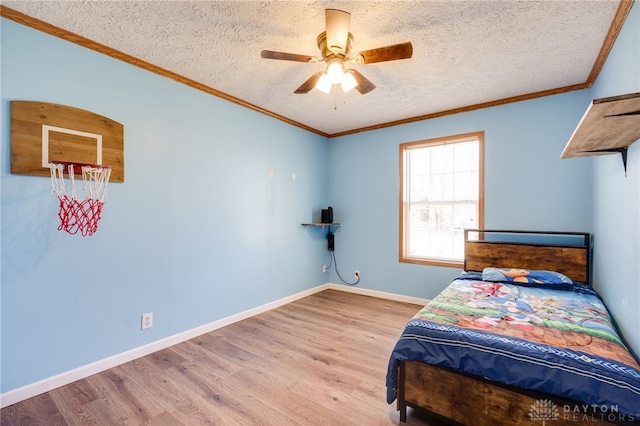 bedroom featuring crown molding, a textured ceiling, baseboards, and wood finished floors