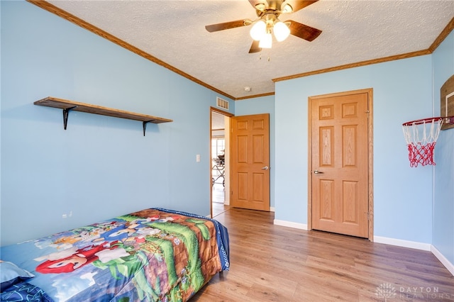 bedroom featuring light wood-type flooring, a textured ceiling, baseboards, and crown molding