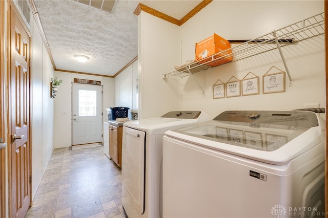 washroom featuring a textured ceiling, washing machine and dryer, visible vents, and crown molding