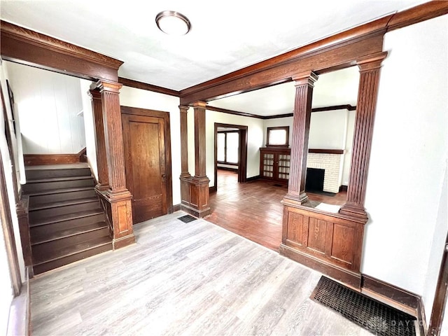 foyer with light wood-type flooring, ornate columns, stairs, and a fireplace