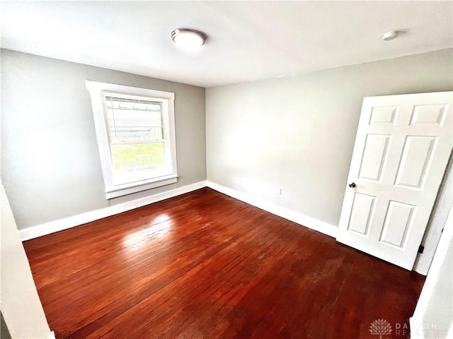 unfurnished room with baseboards and hardwood / wood-style floors