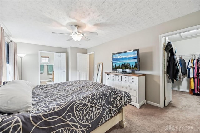 carpeted bedroom featuring a textured ceiling, a spacious closet, baseboards, and a closet