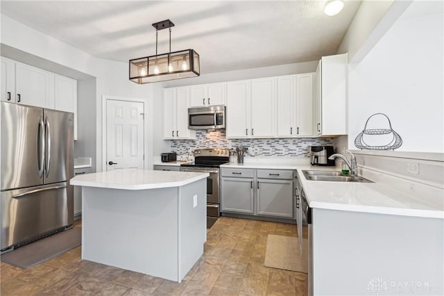 kitchen featuring a center island, light countertops, backsplash, appliances with stainless steel finishes, and a sink