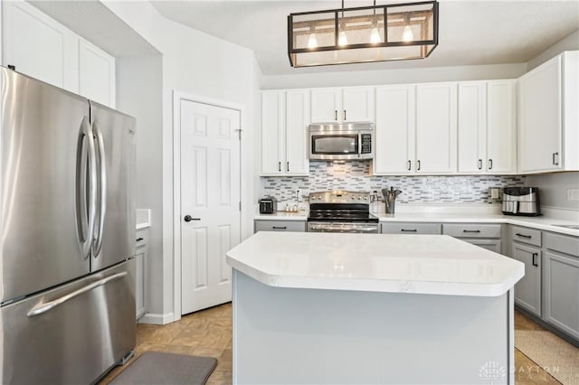 kitchen featuring a kitchen island, light countertops, appliances with stainless steel finishes, backsplash, and gray cabinets