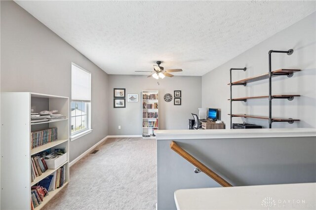 office space featuring a textured ceiling, ceiling fan, visible vents, baseboards, and carpet