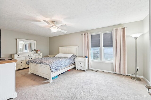 bedroom with visible vents, a ceiling fan, light carpet, a textured ceiling, and baseboards