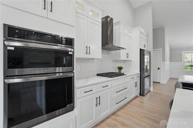 6976 Rosecliff Pl, Dayton, OH 45459 - kitchen with appliances with stainless steel finishes, wall chimney range hood, white cabinetry, glass insert cabinets, and light wood-type flooring