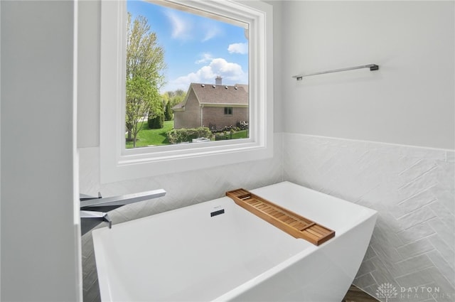 6976 Rosecliff Pl, Dayton, OH 45459 - bathroom featuring tile walls, a freestanding tub, healthy amount of natural light, and a wainscoted wall