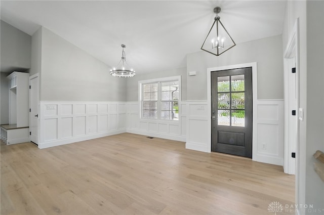 6976 Rosecliff Pl, Dayton, OH 45459 - entryway featuring a chandelier, vaulted ceiling, a decorative wall, light wood-style floors, and wainscoting
