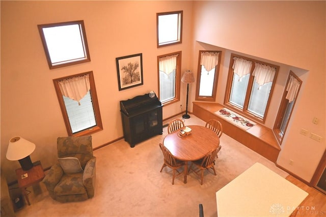 interior space with carpet floors, a towering ceiling, and baseboards