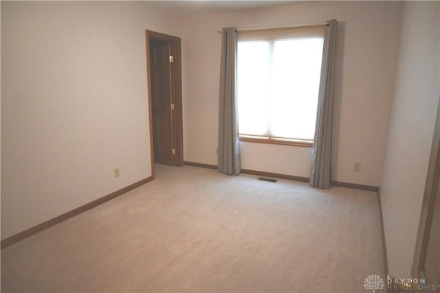 unfurnished room featuring visible vents, light carpet, and baseboards