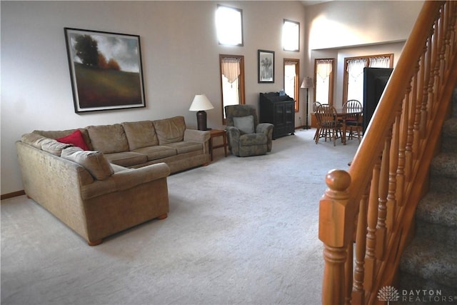 carpeted living room with a towering ceiling, baseboards, and stairs