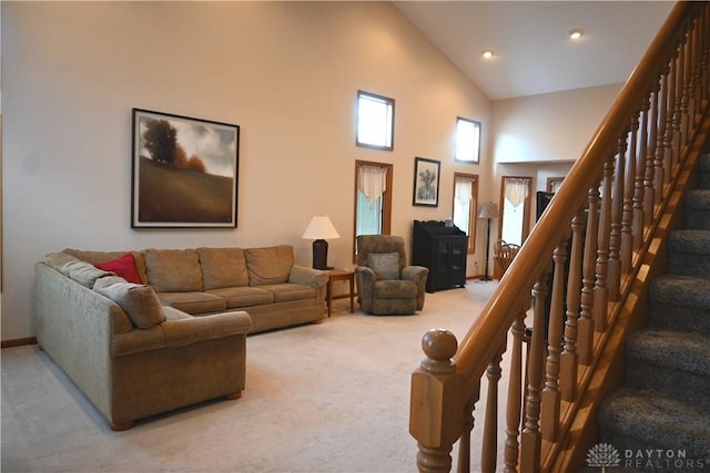 living room featuring stairs, high vaulted ceiling, and carpet flooring