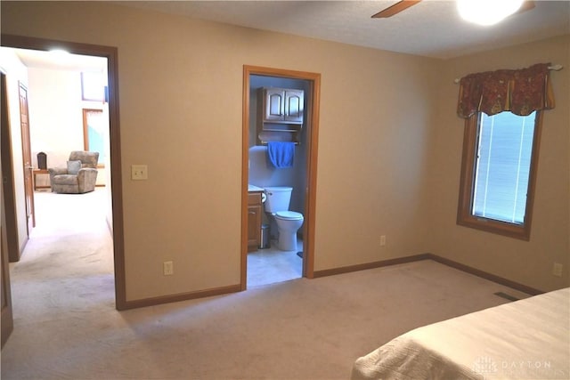 carpeted bedroom with ensuite bathroom, visible vents, and baseboards