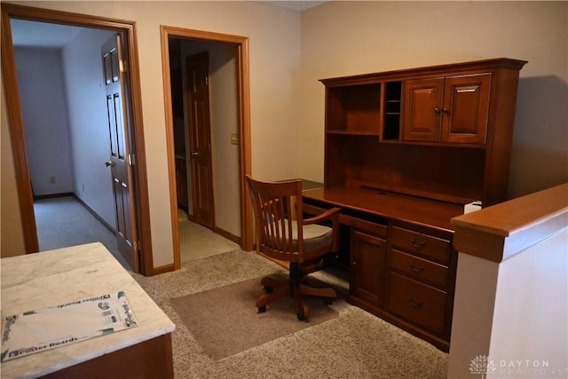 office area featuring light colored carpet, built in study area, and baseboards