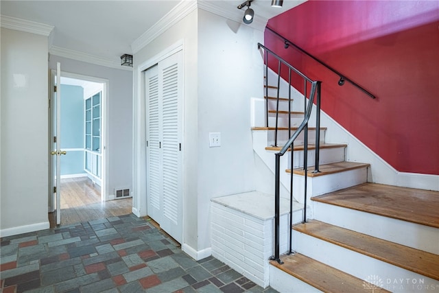 stairway featuring ornamental molding, track lighting, visible vents, and baseboards