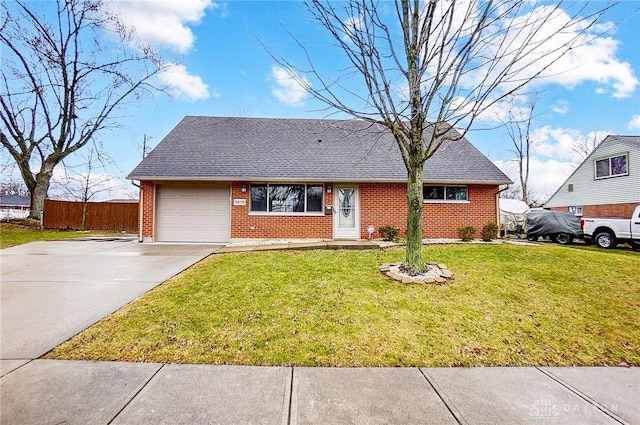 view of front of house featuring a front lawn, driveway, fence, an attached garage, and brick siding