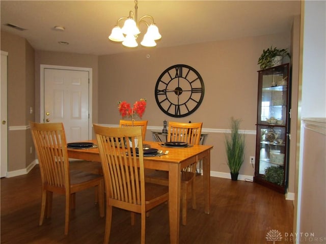 dining room featuring an inviting chandelier, visible vents, baseboards, and wood finished floors