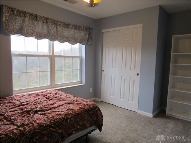 carpeted bedroom featuring a closet and baseboards