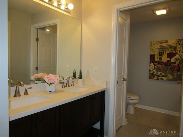 full bathroom with double vanity, a sink, toilet, and tile patterned floors