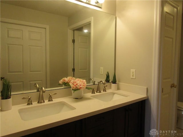 full bath with double vanity, toilet, and a sink