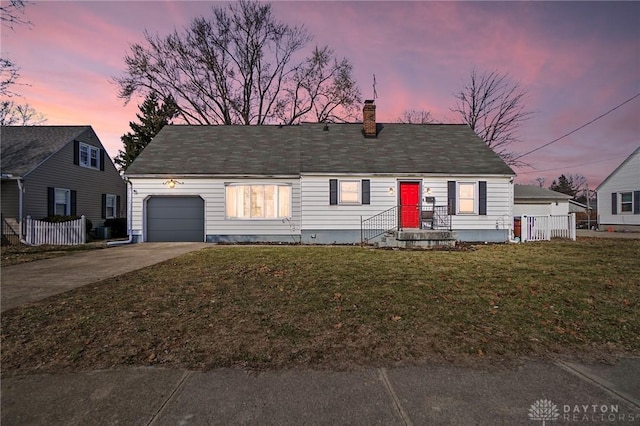 view of front facade with a yard, a chimney, fence, a garage, and driveway