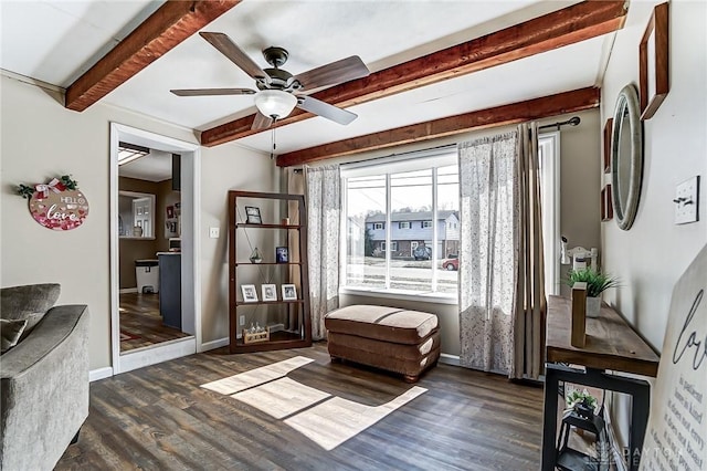 living area featuring a ceiling fan, baseboards, beam ceiling, and wood finished floors