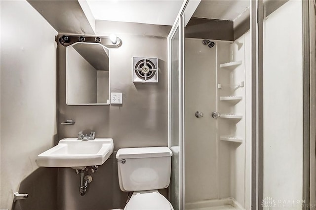 bathroom featuring a stall shower, a sink, and toilet