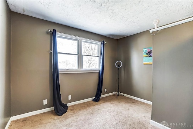 carpeted spare room with baseboards and a textured ceiling