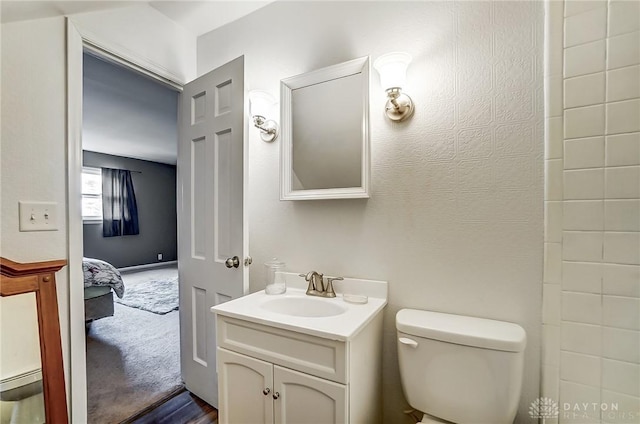 bathroom with ensuite bath, vanity, and toilet