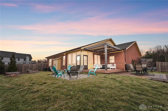 back of property featuring a yard, an outdoor fire pit, fence, and brick siding