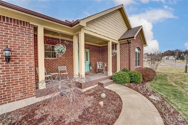 view of exterior entry with covered porch and brick siding