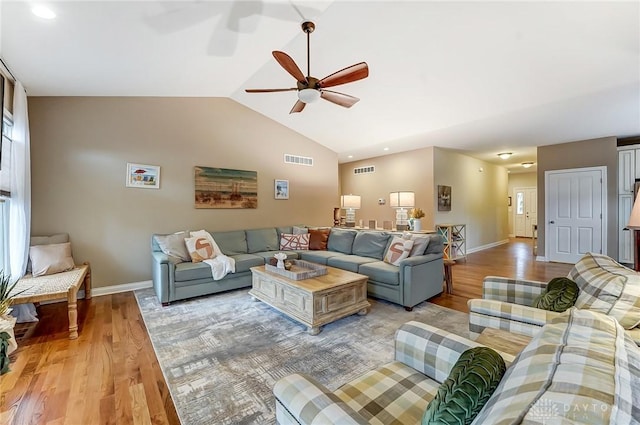 living area featuring lofted ceiling, light wood-style flooring, and visible vents