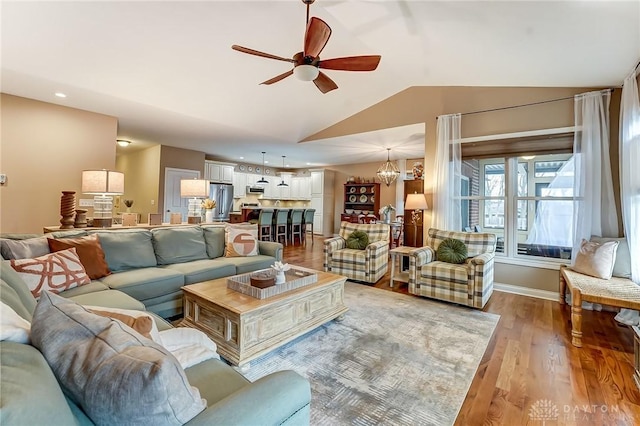 living room with baseboards, lofted ceiling, ceiling fan with notable chandelier, light wood-style floors, and recessed lighting