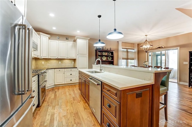 kitchen with stainless steel appliances, a breakfast bar, a sink, light wood-type flooring, and tasteful backsplash